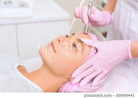 Image of a young beautiful woman dressed as a patient, lying on a couch in a cosmetology clinic. 89909441