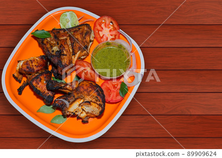 Homemade tandoori chicken served in a plate with salad and chutney on a wooden background. Homemade tandoori chicken served in a plate with salad and chutney on a wooden background. 89909624