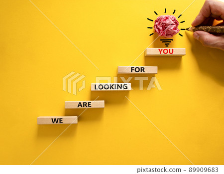 We are looking for you symbol. Wooden blocks with words We are looking for you. Beautiful yellow background, copy space. Businessman hand, light bulb. Business, we are looking for you concept. 89909683