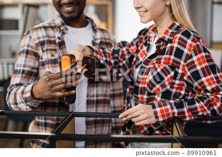 Close up of couple using screwdriver for assembling bookcase Close up of couple using screwdriver for assembling bookcase 89910961