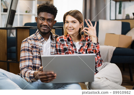 Family sitting at new flat with laptop and holding keys Family sitting at new flat with laptop and holding keys 89910982