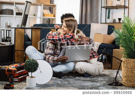 Happy family using laptop and embracing on floor Happy family using laptop and embracing on floor 89910988