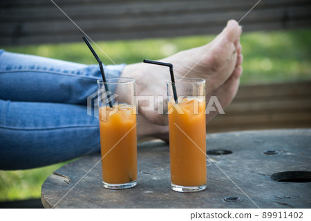 Closeup of two glasses of cocktail at the bar terrace in outdoor with woman feet on background 89911402