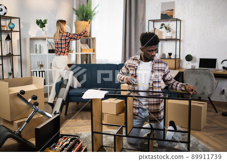 Diverse young family improving interior at new flat Diverse young family improving interior at new flat 89911739