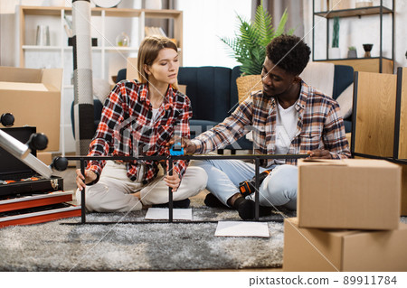 Multiracial couple assembling furniture at home Multiracial couple assembling furniture at home 89911784