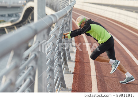 Horizontal side view of modern senior man wearing tracksuit doing aerobic exercise 89911913