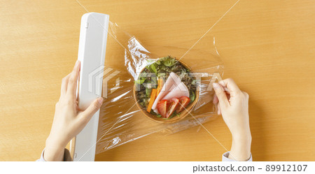 使用食品保鮮膜存儲沙拉的女人。食品保鮮、保鮮等。 89912107