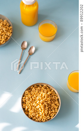 Breakfast concept with cold cereals and orange juice on blue background Breakfast concept with cold cereals and orange juice on blue background 89912202