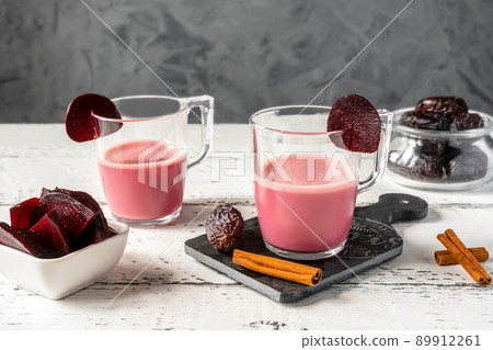 Healthy and tasty beetroot latte in two mugs with basic ingredients Healthy and tasty beetroot latte in two mugs with basic ingredients 89912261
