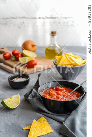 Tomato dip with nachos tortilla in bowl and main ingredients aside 89912292