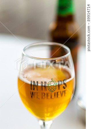 Glass of craft beer with "In Hops We Believe" text 89914714