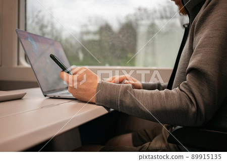 A male traveler works online on a European train while traveling by train. Unrecognizable man A male traveler works online on a European train while traveling by train. Unrecognizable man 89915135