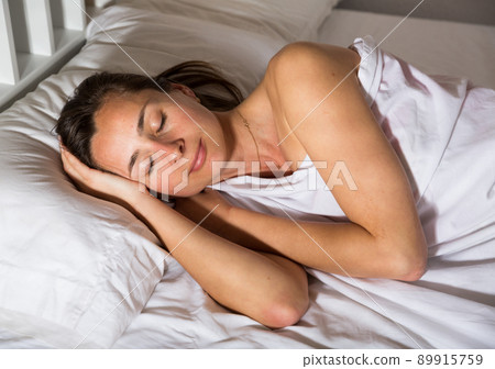 Adult female is sleeping on bed in bedroom at home 89915759