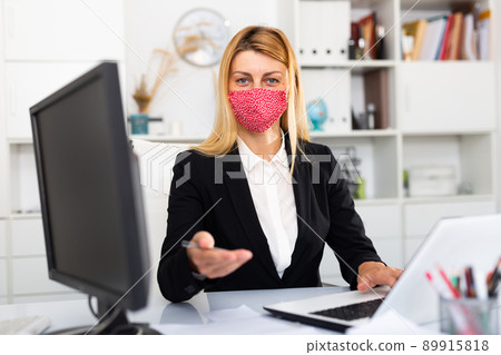Businesswoman in colored medical mask working with laptop 89915818