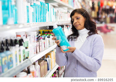 Woman choosing hair shampoo in cosmetics store 89916205