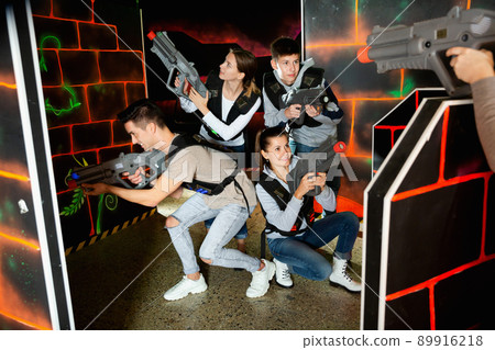 Ordinary Laser tag players young mens and womens playing in teams in dark laser tag station 89916218