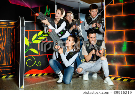Modern young people with laser pistols playing laser tag on dark labyrinth 89916219