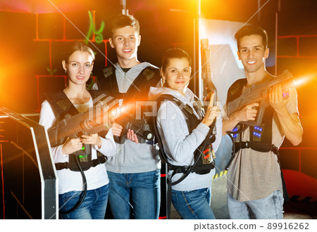 Happy young people with laser pistols posing together on dark la 89916262