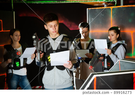 Group of young people with laser guns carefully read equipment rental agreement 89916273