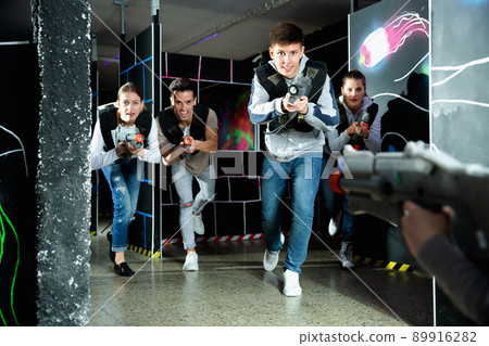 Portrait of teenager boy with laser gun having fun on dark lasertag arena Portrait of teenager boy with laser gun having fun on dark lasertag arena 89916282