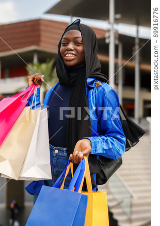 Stylish Muslim woman with shopping bags outside mall Stylish Muslim woman with shopping bags outside mall 89916776