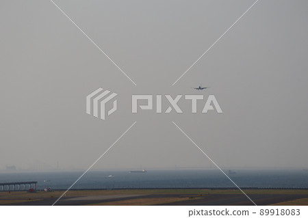 A view of the airport with a blue sea, a hazy tanker, a cityscape, the sky, and a runway where planes fly to land. A view of the airport with a blue sea, a hazy tanker, a cityscape, the sky, and a runway where planes fly to land. 89918083