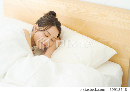 A woman sleeping in bed in her 20s 89918548