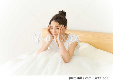 A woman holding her head, a futon 89918648