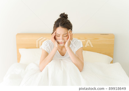 A woman holding her head, a futon 89918649