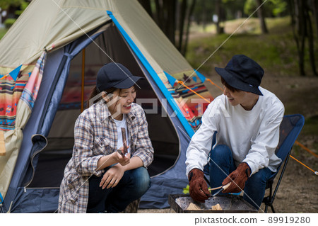 A boy who wears a fire with a fire starter and a girl who watches over it 89919280