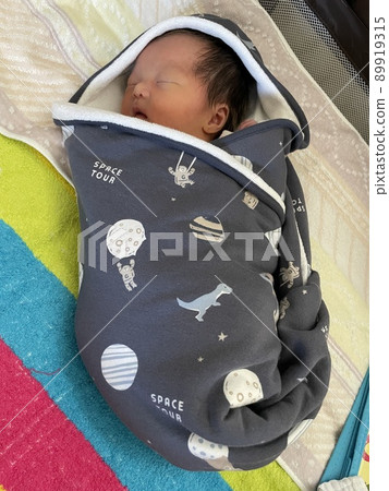 A very small newborn girl sleeping wrapped in a swaddle. 89919315