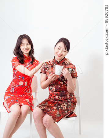 Portrait of Asian Young daughter giving her mother a massage for Relieve stress on white background(both wearing traditional cheongsam qipao dress). Portrait of Asian Young daughter giving her mother a massage for Relieve stress on white background(both wearing traditional cheongsam qipao dress). 89920783