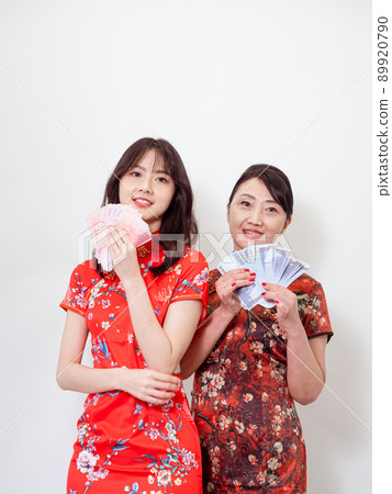 Portrait of mature asian mother and her asian daughter both wearing traditional cheongsam qipao dress holding bunch of money banknotes on white background. Portrait of mature asian mother and her asian daughter both wearing traditional cheongsam qipao dress holding bunch of money banknotes on white background. 89920790