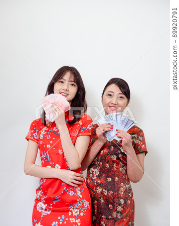 Portrait of mature asian mother and her asian daughter both wearing traditional cheongsam qipao dress holding bunch of money banknotes on white background. Portrait of mature asian mother and her asian daughter both wearing traditional cheongsam qipao dress holding bunch of money banknotes on white background. 89920791