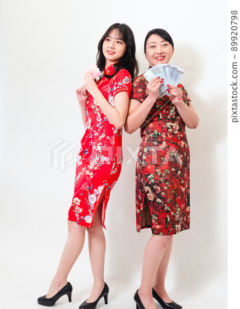 Portrait of mature asian mother and her asian daughter both wearing traditional cheongsam qipao dress holding bunch of money banknotes on white background. Portrait of mature asian mother and her asian daughter both wearing traditional cheongsam qipao dress holding bunch of money banknotes on white background. 89920798