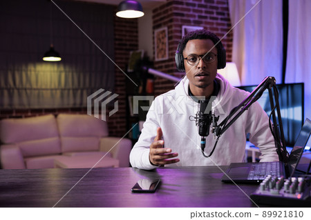 POV of young influencer recording podcast episode on camera, talking into microphone for sound production. Male blogger filming livestream vlog to create social media web content. POV of young influencer recording podcast episode on camera, talking into microphone for sound production. Male blogger filming livestream vlog to create social media web content. 89921810