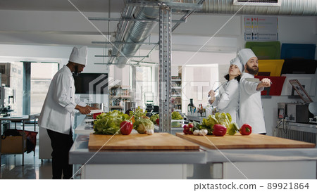 Man and woman cooks acting funny with knives in kitchen, advertising professional meal preparations. Team of chefs feeling cheerful and using organic ingredients to cook gourmet meal. Man and woman cooks acting funny with knives in kitchen, advertising professional meal preparations. Team of chefs feeling cheerful and using organic ingredients to cook gourmet meal. 89921864