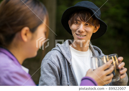 A couple toasting with wine while barbecuing in the forest 89922007
