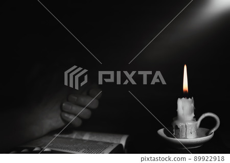 Holy bible and praying man's hands and burning candle background with bright rays of light Holy bible and praying man's hands and burning candle background with bright rays of light 89922918