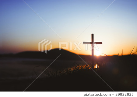 耶穌基督在草地上的聖十字架與夕陽天空的強烈光芒象徵著死亡和復活的愛 耶穌基督在草地上的聖十字架與夕陽天空的強烈光芒象徵著死亡和復活的愛 89922925