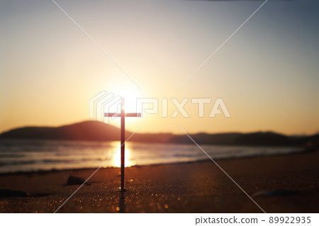 The red sunset on the seashore and the sandy beach with strong light reflections and the Holy Cross of Jesus Christ 89922935