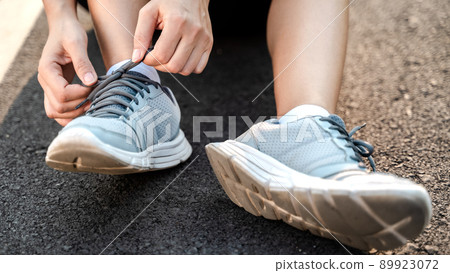 closeup of young woman runner tying her shoelaces. healthy and fitness concept. closeup of young woman runner tying her shoelaces. healthy and fitness concept. 89923072