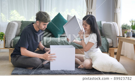 Young couple unpacking cardboard boxes in living room. Relocation house renovation, removals concept 89923782