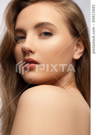 Glamour portrait of beautiful woman model with fresh daily makeup and romantic wavy hairstyle. Fashion shiny highlighter on skin, sexy gloss lips make-up and dark eyebrows 89923885