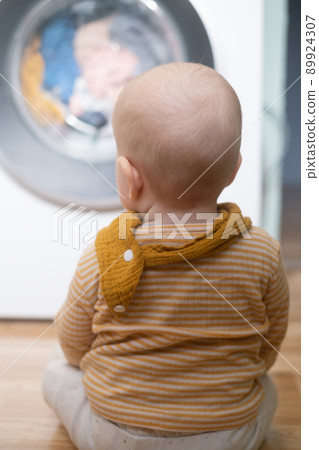 caucasian girl playing with washing machine watching on a process. 89924307