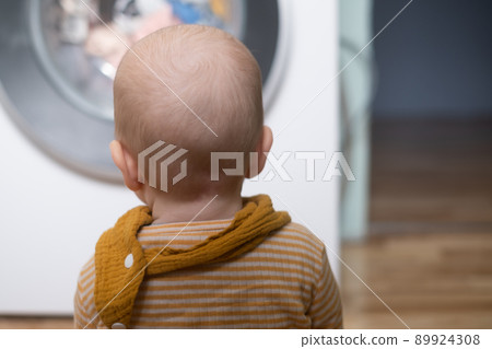 caucasian girl playing with washing machine watching on a process. 89924308