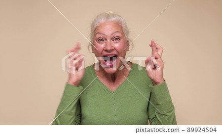 Senior caucasian woman gesturing finger crossed, smiling with hope. Senior caucasian woman gesturing finger crossed, smiling with hope. 89924504