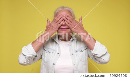 Senior woman closing her eyes waiting for gift on her birthday party Senior woman closing her eyes waiting for gift on her birthday party 89924508