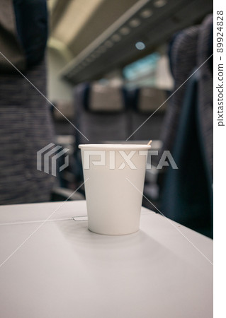 A white disposable coffee cup is on the table on the train. High-speed travel in Europe. Travel by train. 89924828