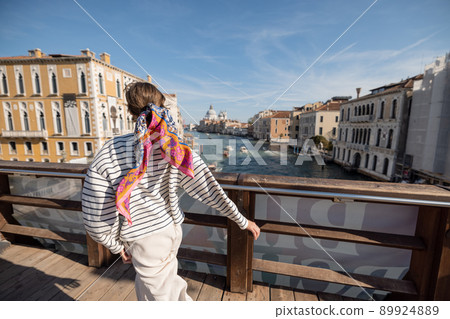 Woman running on the bridge above famous Grand Canal in Venice 89924889
